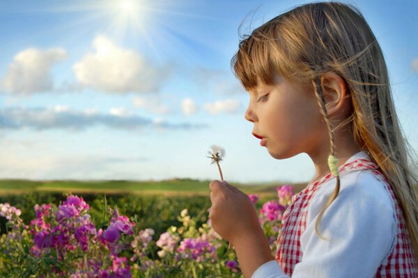 A girl blowing on a dandelion in a field