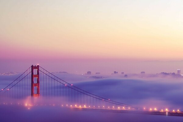 A bridge immersed in thick fog at sunset