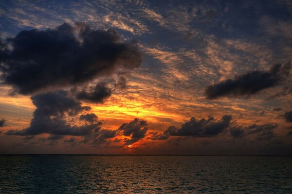 Céu do pôr do sol com nuvens pairando sobre a água