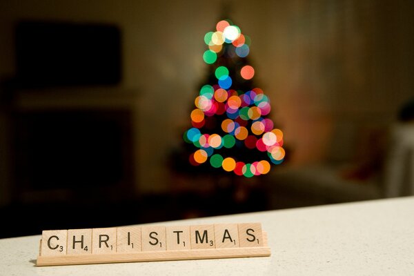 Iscrizione Natale e albero di Natale sfocato con ghirlanda