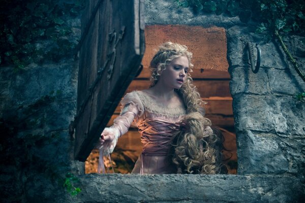 Jeune femme aux cheveux longs regardant par la fenêtre