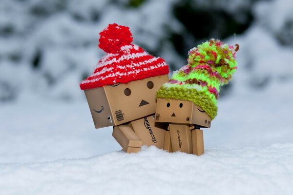 Pappfiguren in Mützen im Schnee