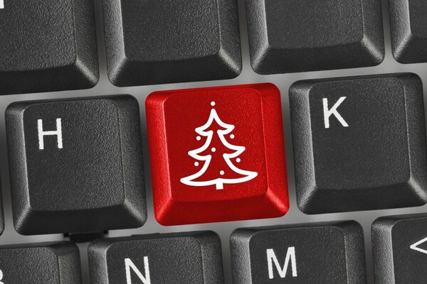 Red button with a picture of a Christmas tree on a black keyboard