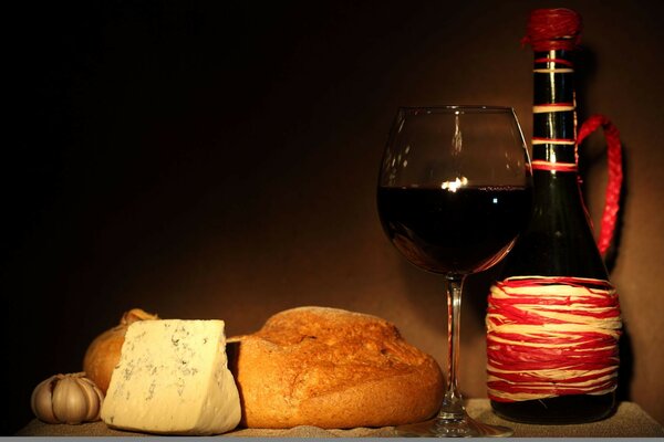 Krug, Glas mit Rotwein, Käse mit Schimmel, Brot, Knoblauch