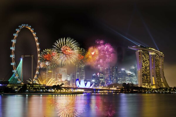 Die Stadt. Feiertag. Vergnügungspark. Feuerwerk. Reflexion der Stadtbeleuchtung im Wasser