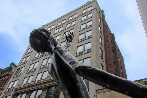 Escultura de un hombre en el fondo de un edificio de gran altura