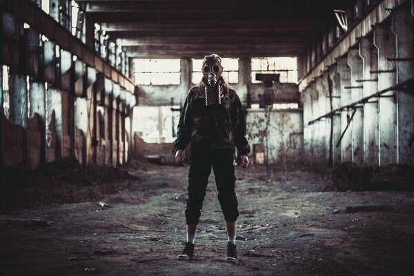 A man with a gas mask is standing in an abandoned building