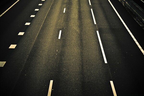 A gloomy asphalt road emerging from the darkness