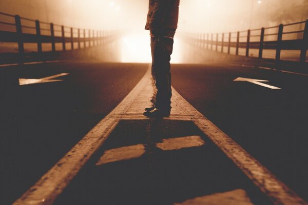 A man whose face is not visible is standing on the bridge