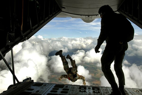 The parachutist jumps out of the hatch of the plane