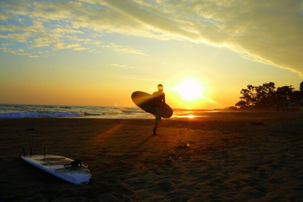 A surfer carries his board for riding