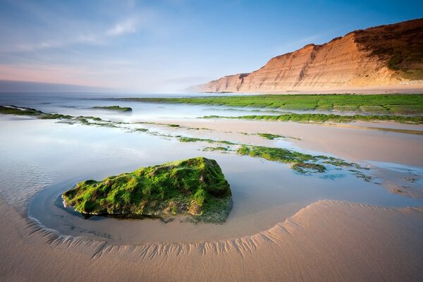 Boulders and stones on the sand against the background of rocks