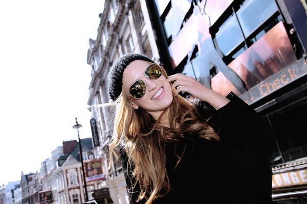 A girl in sunglasses poses on the street