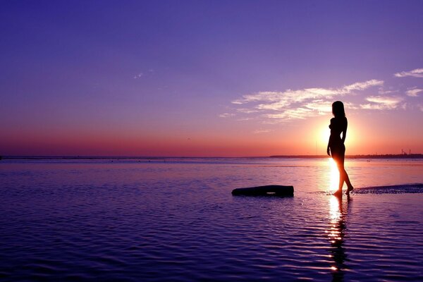 Schönes Foto eines Mädchens bei Sonnenuntergang im Wasser