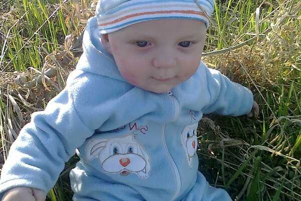 A boy in a blue fleece suit on the grass