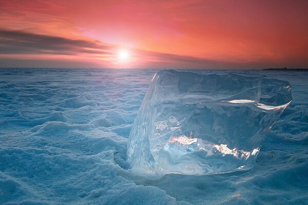 Un gran trozo de hielo en medio de una puesta de sol roja