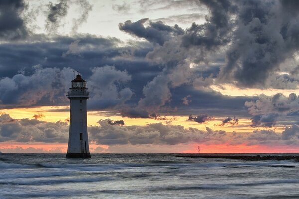 Lighthouse in the sea on the background of clouds