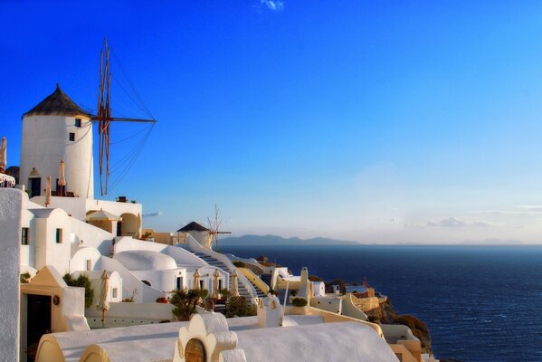 A snow-white lighthouse in the blue sky by the water