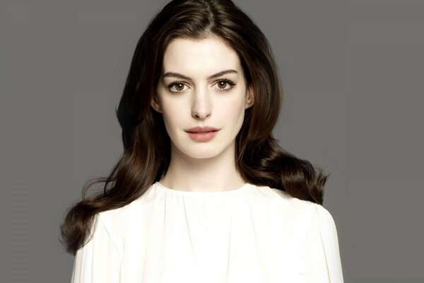 Photo of a brunette with brown eyes in a white blouse on a gray background