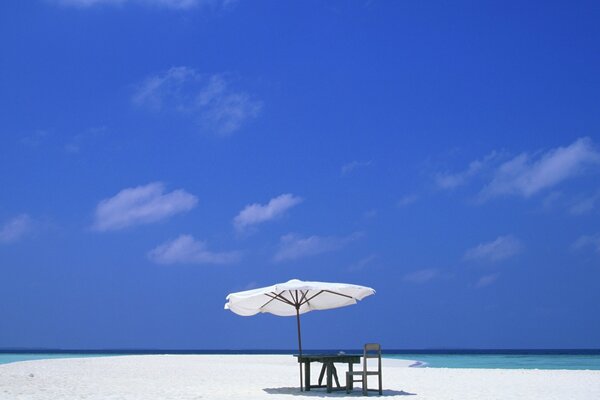 Table under an awning on the beach of the azure sea