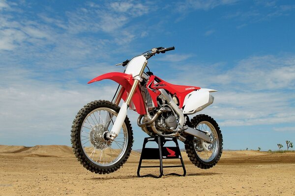 Motocicleta de corrida vermelha e branca legal contra o pano de fundo do deserto