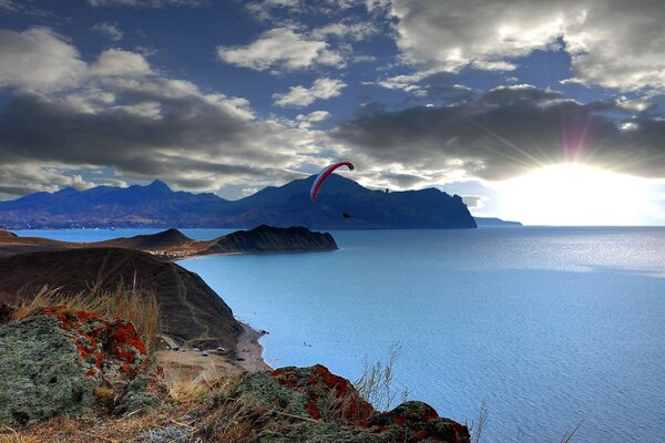 A parachutist on a paraglider flies over the lake