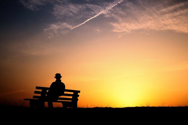 Silhouette di un uomo su una panchina sullo sfondo del tramonto