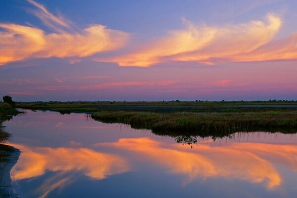 An orange sunset is reflected in the water