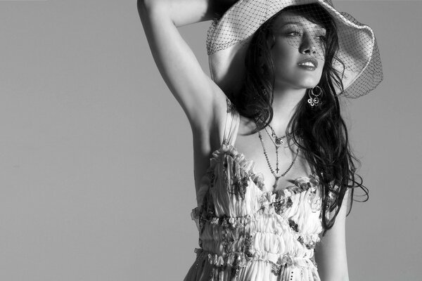 Brunette in a hat and dress on a gray background