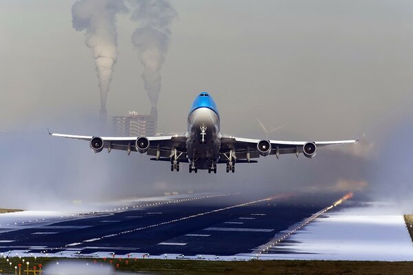 Avión despegando en medio de una casa humeante