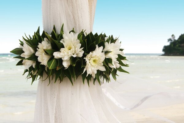 Suporte para um em um tecido branco e decorado com flores brancas no fundo do mar céu azul