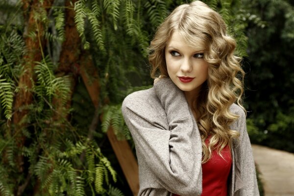 Blonde assise dans le parc sous un arbre