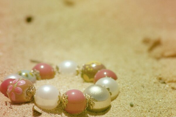 Bracelet made of white and pink beads on the sand