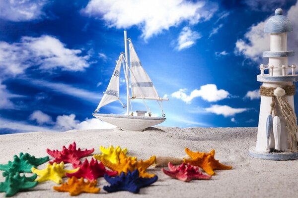 Fotocollage. Eine Yacht mit weißen Segeln. Weißer Sand. Blauer Himmel mit weißen Wolken. Bunte Seesterne