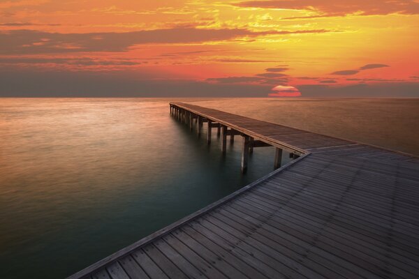 Vista de la puesta de sol desde el muelle de madera junto al mar