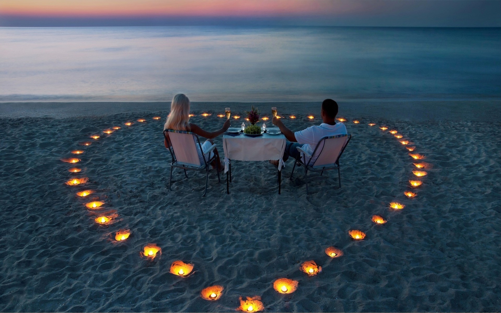 Two lovers for a romantic dinner among candles on the sea. Android