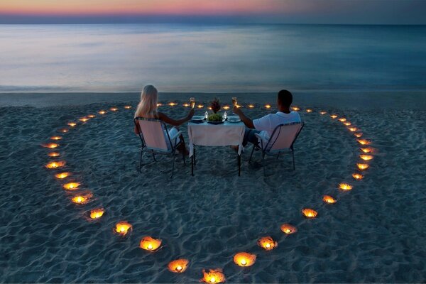 Two lovers having a romantic dinner among candles on the sea