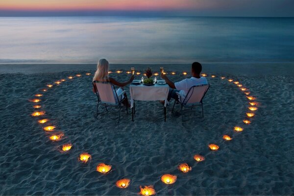 Deux amoureux derrière un dîner romantique au milieu des bougies sur la mer