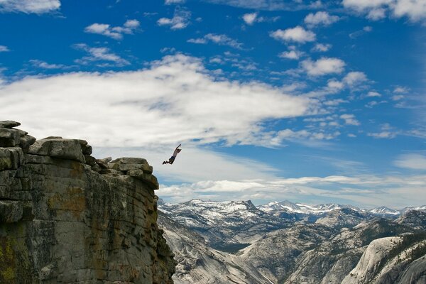 An athlete jumps down from a huge cliff