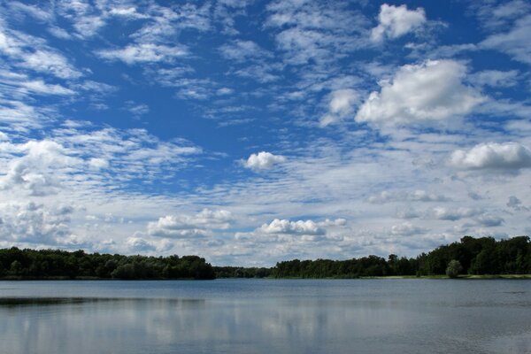 المناظر الطبيعية للبحيرة والأشجار والسماء الزرقاء مع الغيوم