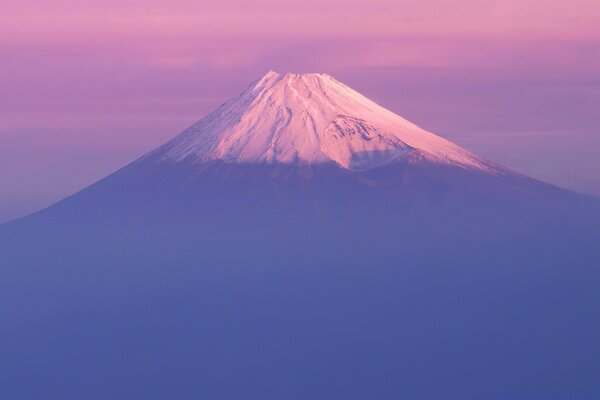 Volcan enneigé dans le brouillard rose-violet