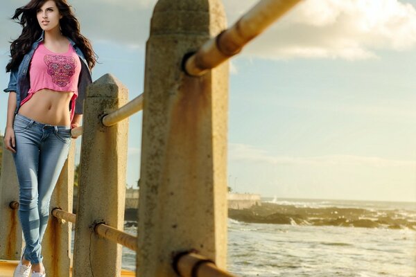 A girl at sunset is standing on the pier