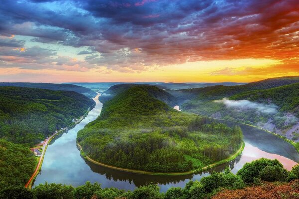 Bild von einem Flussdelta, das sich mitten in einem grünen Wald und Bergen verbiegt