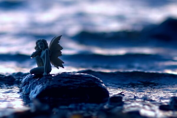 Donna con le ali su una pietra vicino al mare