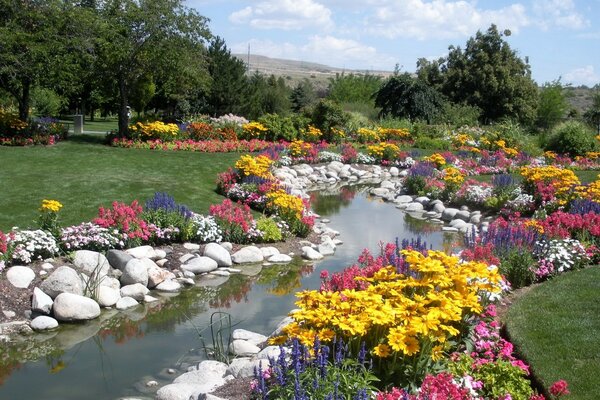 Un sinuoso arroyo de piedras blancas a lo largo de las orillas que fluye en medio de un Prado lleno de flores