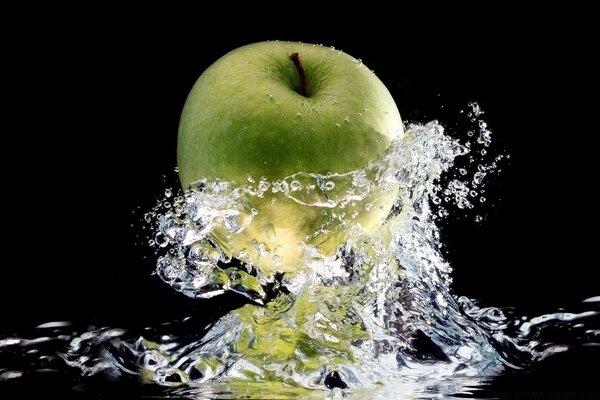 Falling green apple into the water