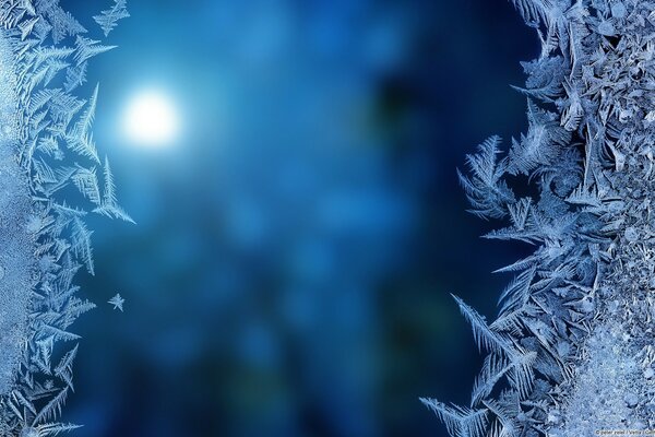 Frosty pattern on the window on the background of a moonlit night