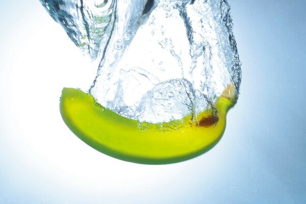 A green banana fell into clear water