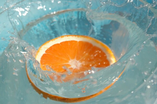 Eine Orangenscheibe fiel in ein Glas Wasser