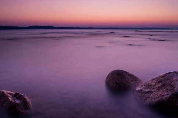 Sonnenuntergang am Strand mit Felsbrocken und Steinen